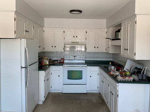 a white kitchen with a stove and a refrigerator