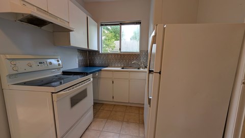 A kitchen with white appliances and cabinets.