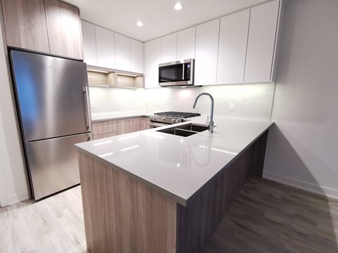 A modern kitchen with a stainless steel refrigerator and a white countertop.
