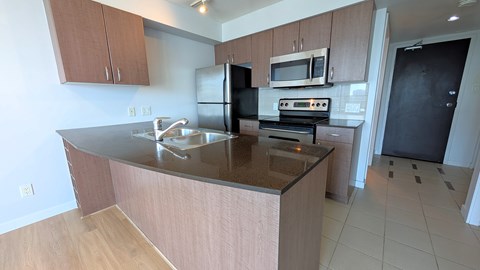 A kitchen with a black refrigerator and a stove top oven.
