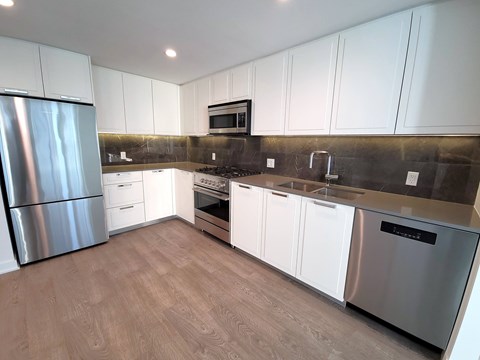 A modern kitchen with white cabinets and stainless steel appliances.