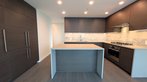 A modern kitchen with dark brown cabinets and a white island.