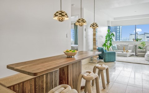 A modern kitchen with a wooden counter and stools.