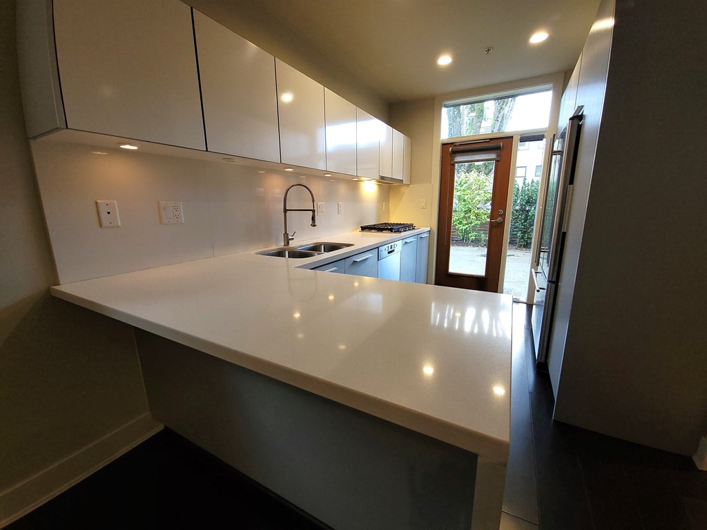 A kitchen with white countertops and cabinets.