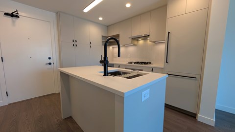 A modern kitchen with a white island and stainless steel appliances.