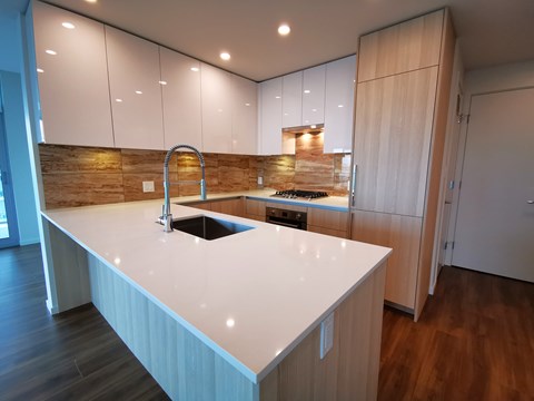 A modern kitchen with a white countertop and wooden cabinets.