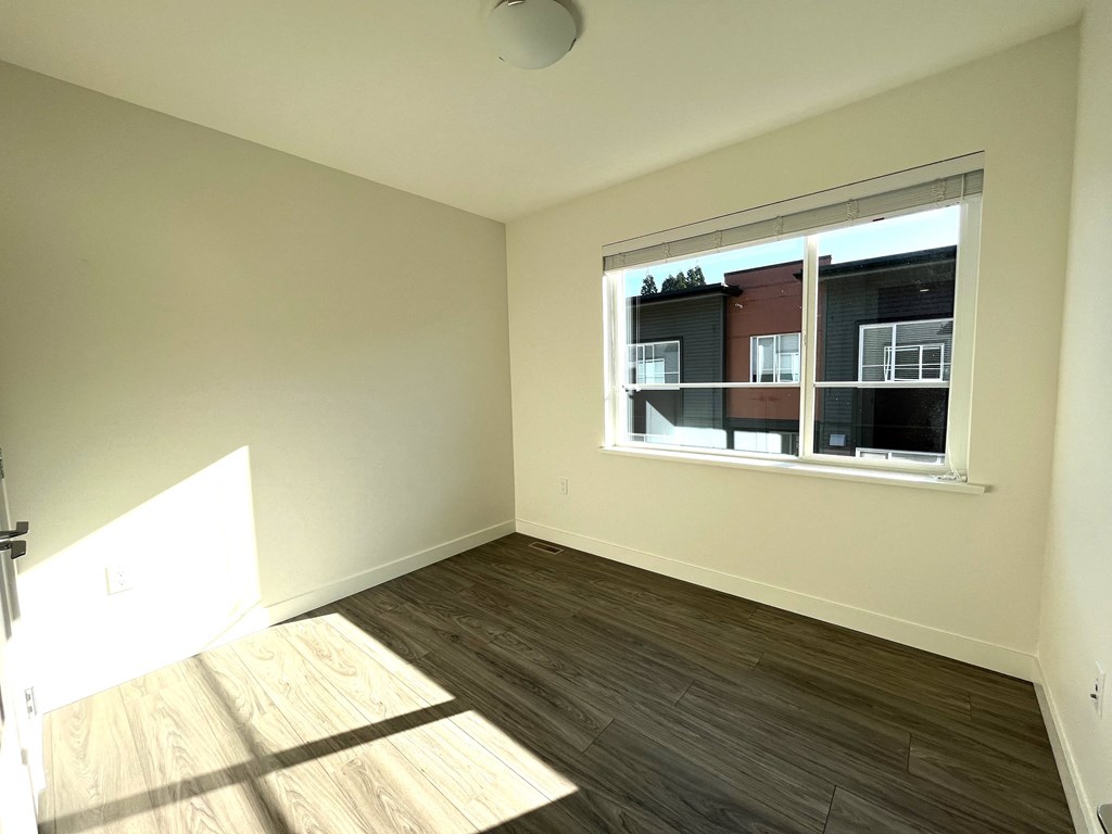 an empty living room with a window and wood floors