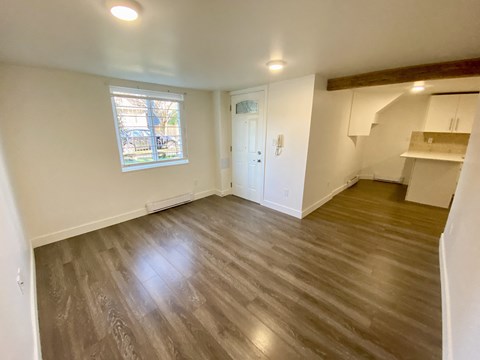 an empty living room with wooden floors and a window