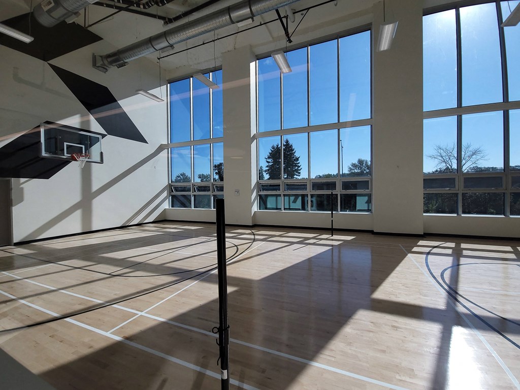 an empty gym with large windows and a wooden floor