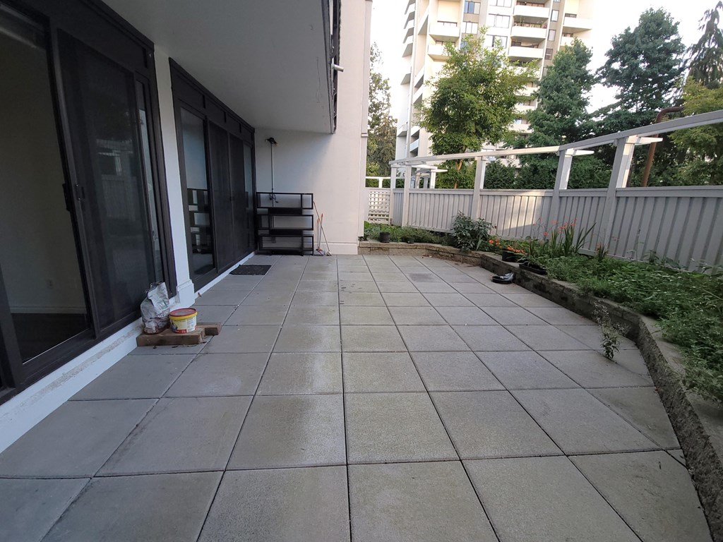 a patio with a tiled floor and a white fence