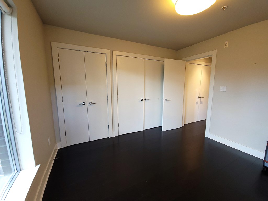 A room with four white doors and a window on the left side.
