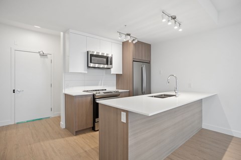 A modern kitchen with a white countertop and wooden cabinets.