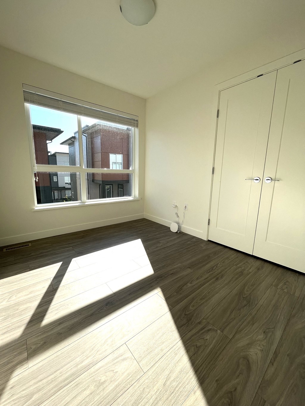 an empty living room with a large window and wooden floors