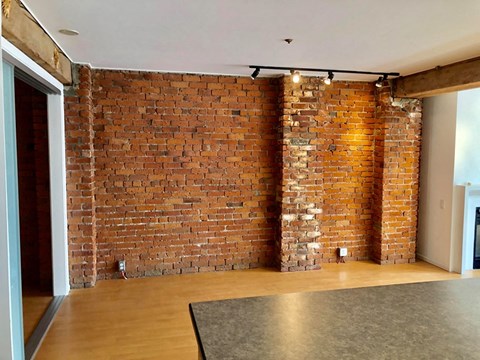 an exposed brick wall in a living room with wood floors and a rug