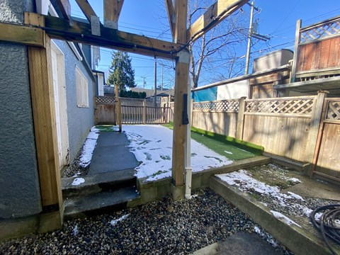 a backyard with a wooden fence and a walkway in the snow