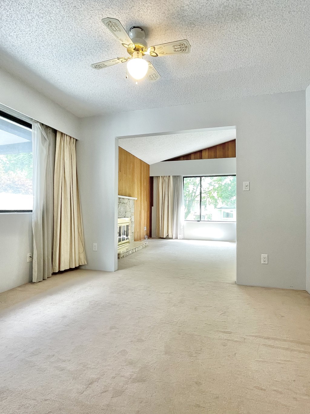 an empty living room with a ceiling fan