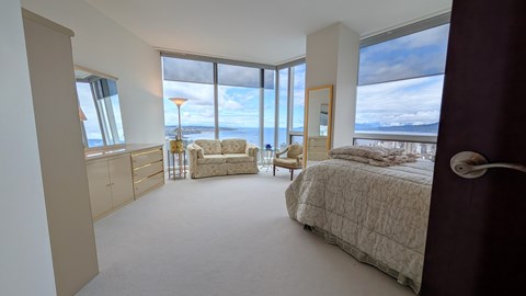 A bedroom with a large bed and a view of the ocean.