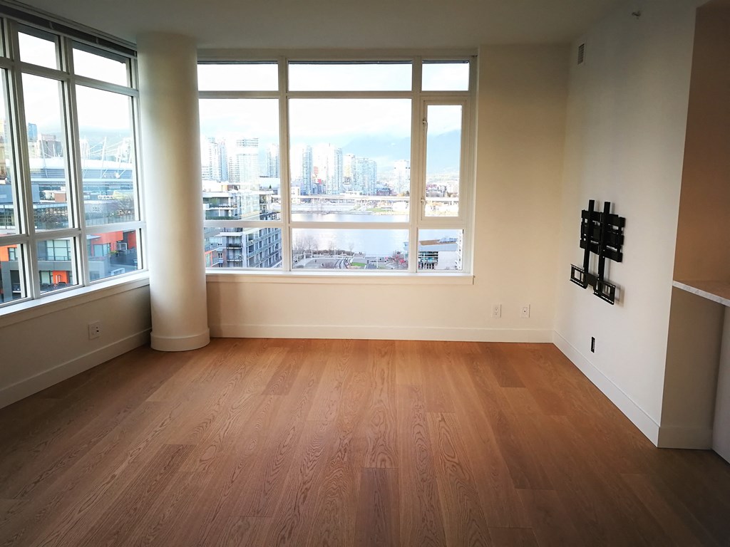 an empty living room with wood floors and a view of the city