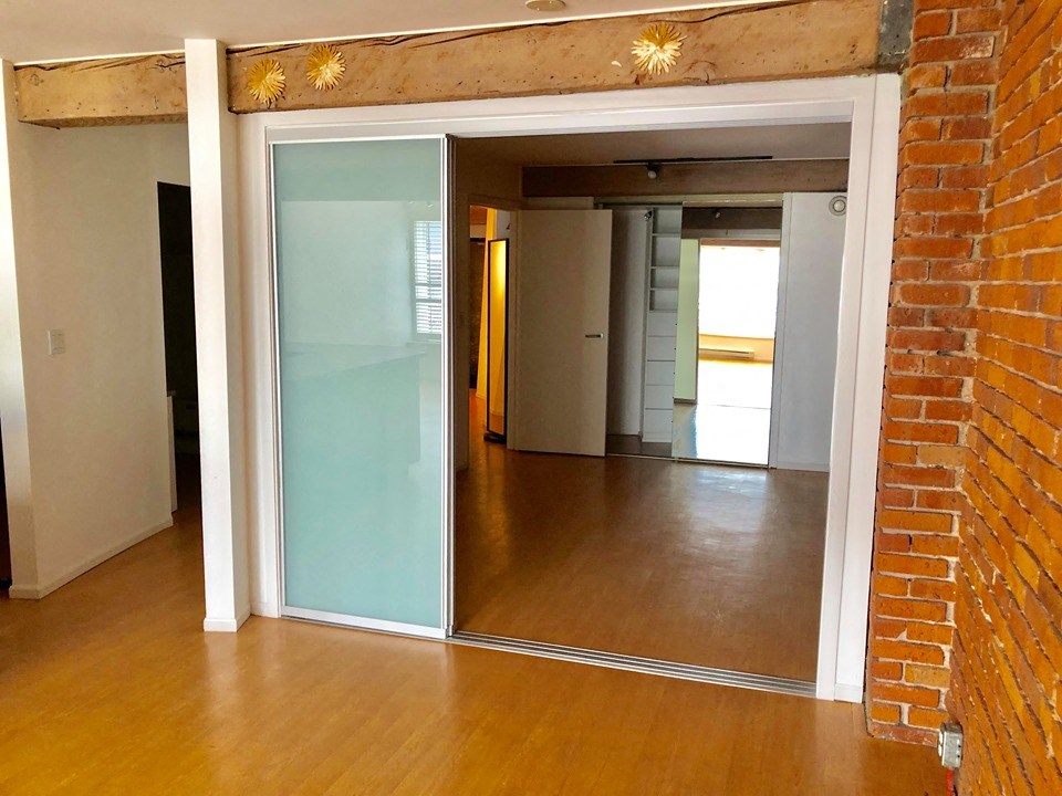 an empty living room with a mirror and a brick wall