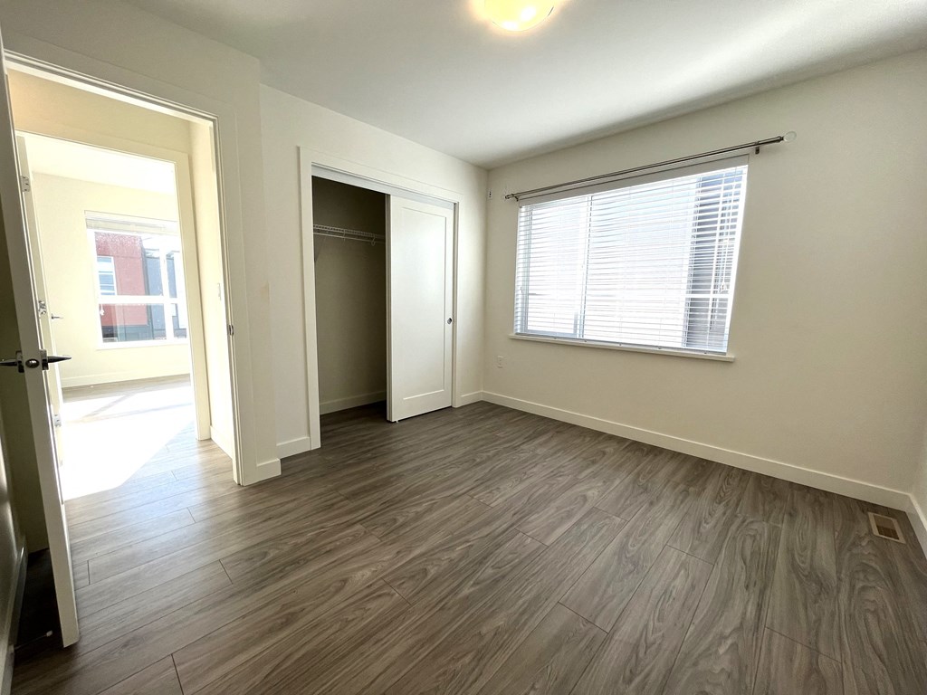 an empty living room with wood flooring and a window
