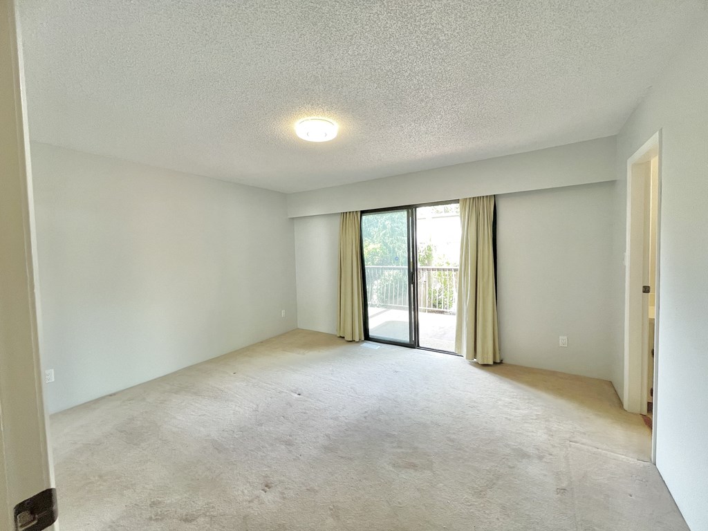 an empty living room with sliding glass doors to a patio
