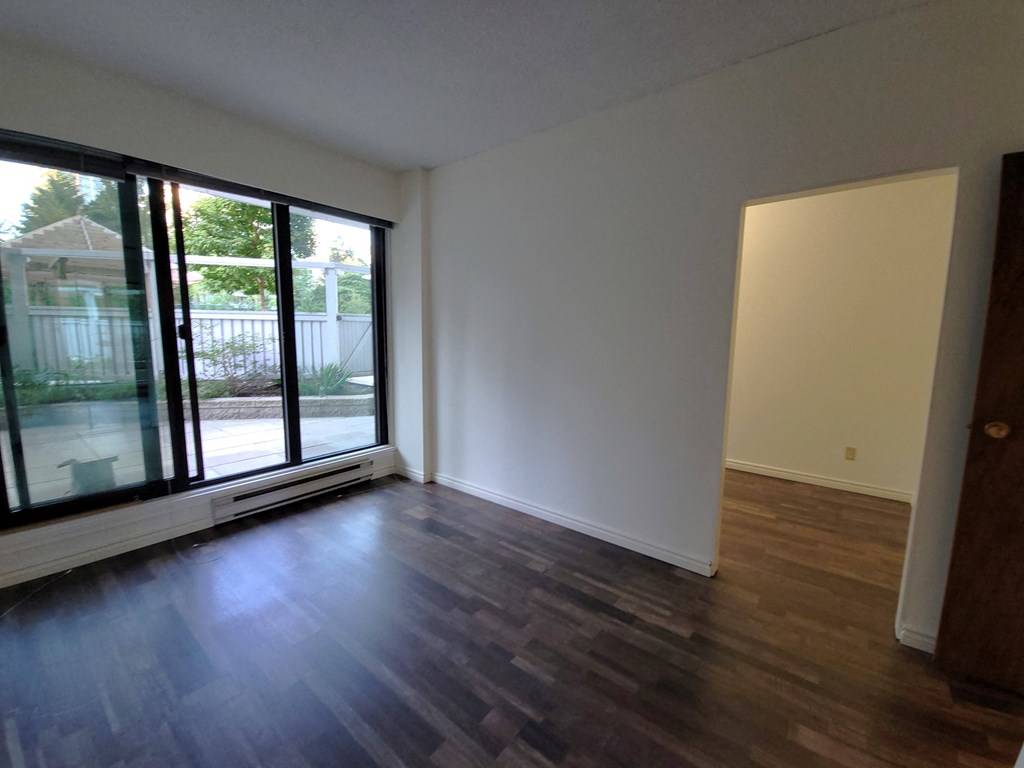 an empty living room with wood floors and a patio door