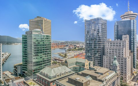 A cityscape with a large body of water in the foreground and several tall buildings in the background.
