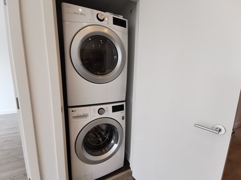 Two washing machines are stacked in a small space.