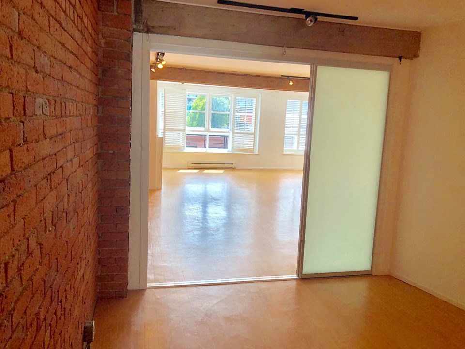 an empty living room with a brick wall and a sliding glass door