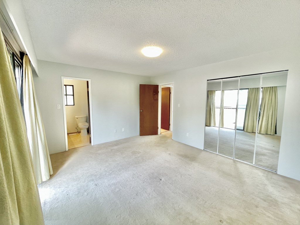 an empty living room with a bathroom and sliding glass doors