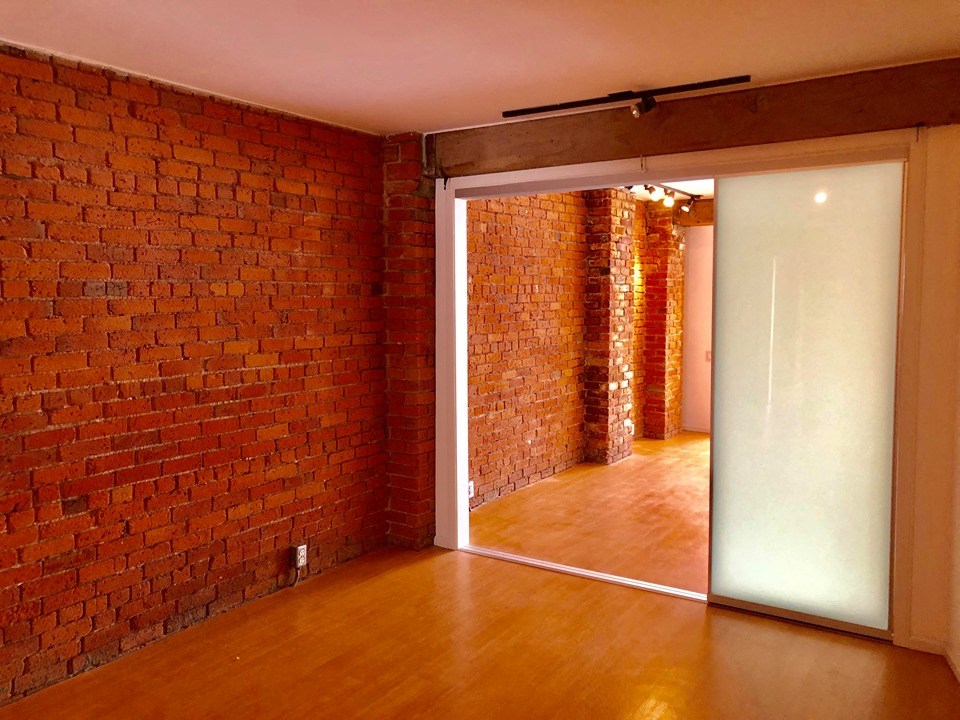 an empty room with a brick wall and a sliding glass door