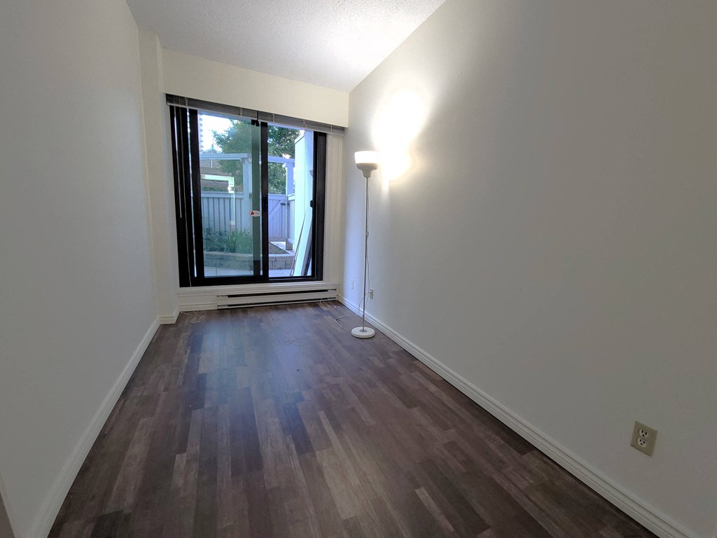 an empty living room with a window and wood flooring