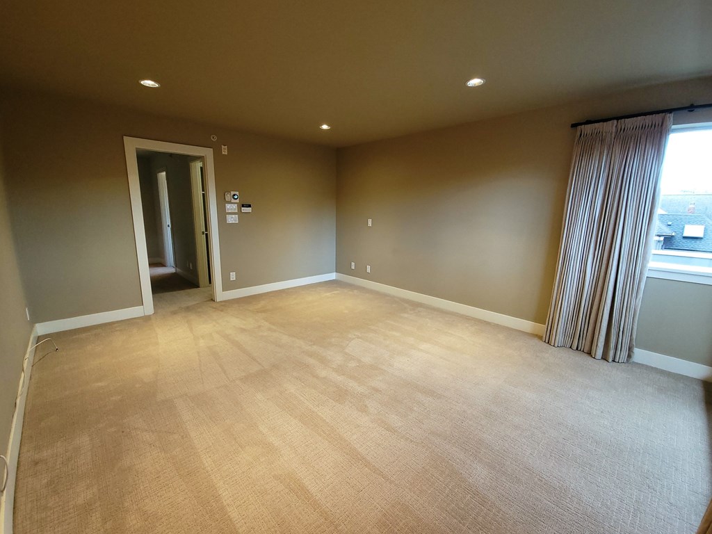 A room with a carpeted floor and a window with curtains.