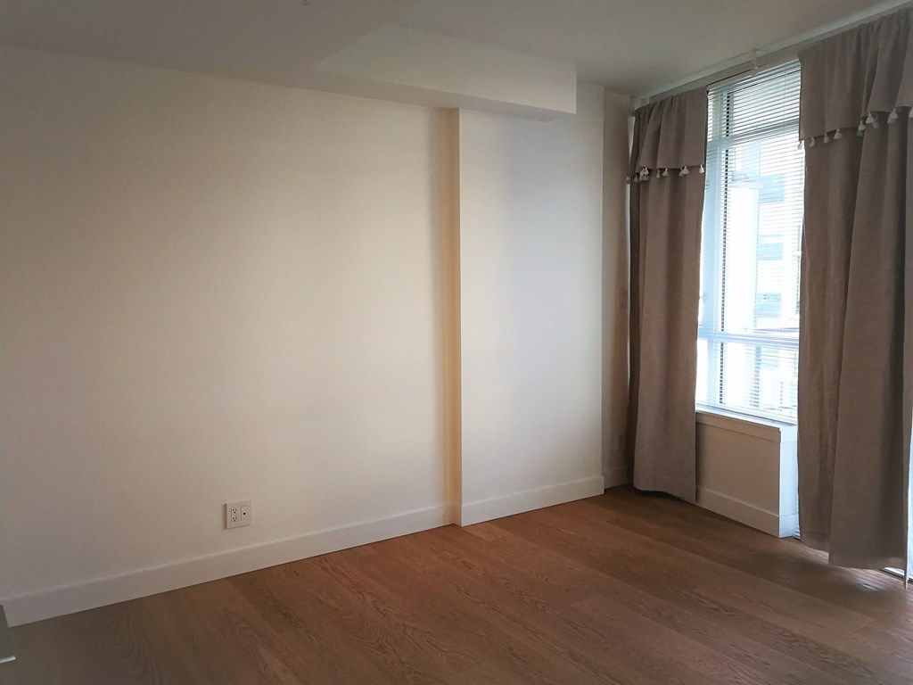 a living room with white walls and a window and wooden floors
