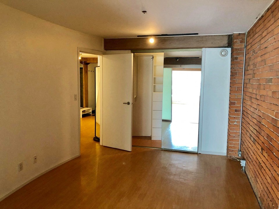 an empty living room with a brick wall and wooden floors