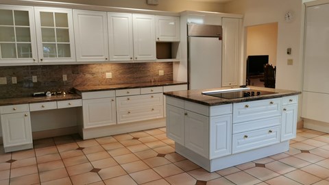 A kitchen with white cabinets and a black countertop.