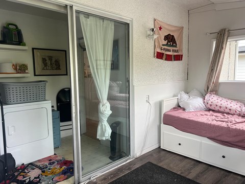 A bedroom with a bed, a window with curtains, and a flag on the wall.