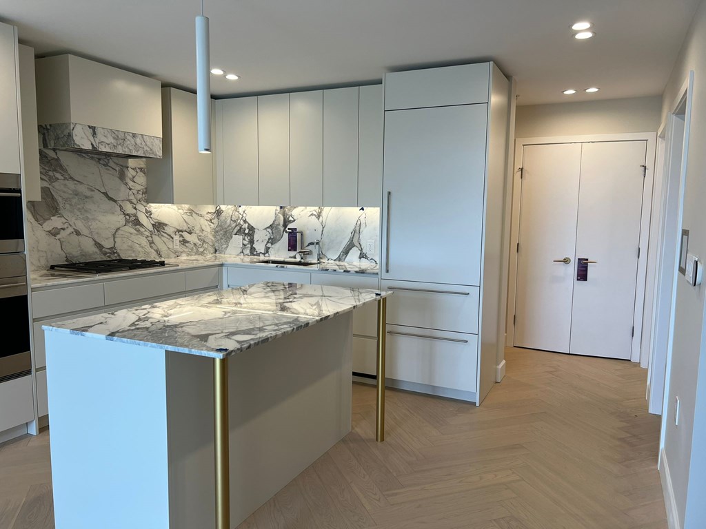 A kitchen with a marble countertop and white cabinets.