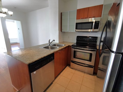 A kitchen with a black dishwasher and stove top oven.