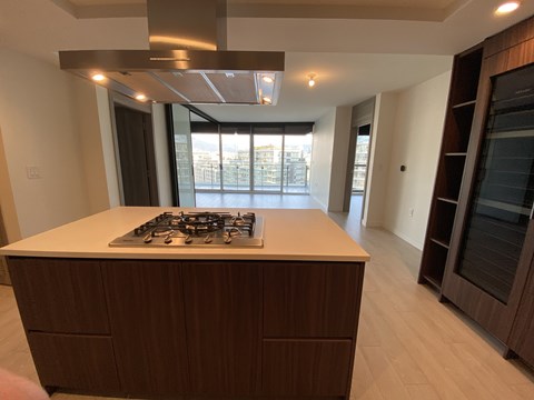 A kitchen with a stove top oven and wooden cabinets.