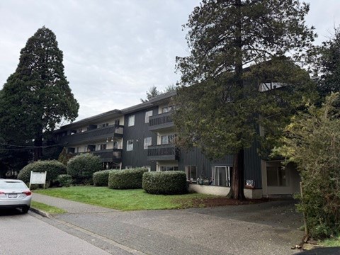 A grey building with a white car parked in front.