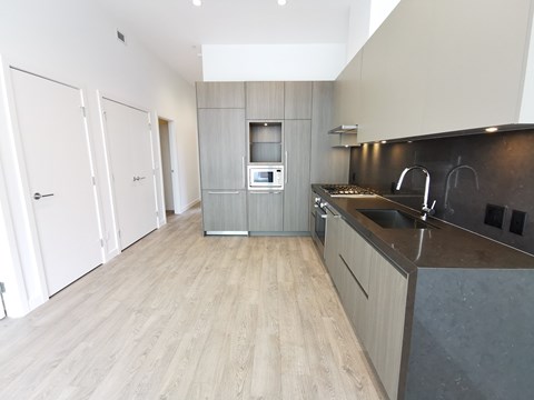 A modern kitchen with a wooden floor and a dark counter.