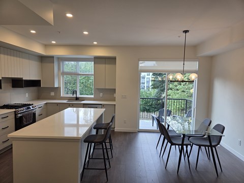 A kitchen with a white counter top and black chairs.