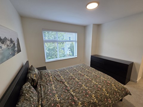A bedroom with a bed, dresser, and window.