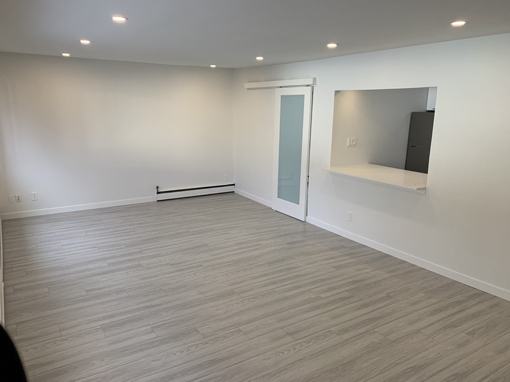 an empty living room with wood floors and a window