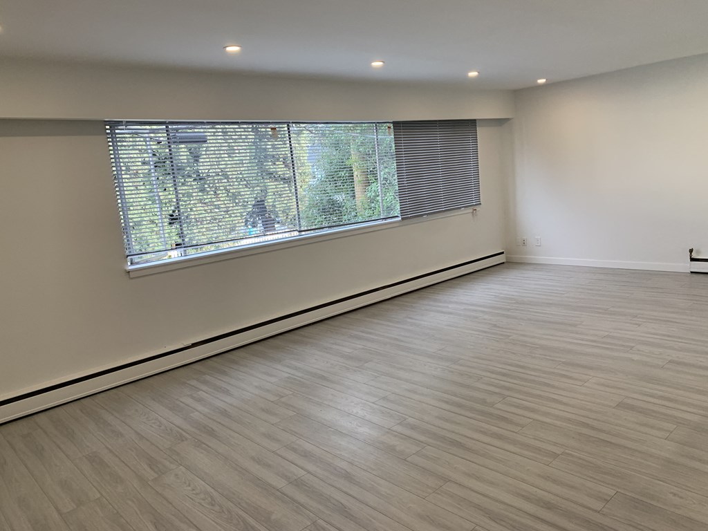 an empty room with a large window and wooden floors