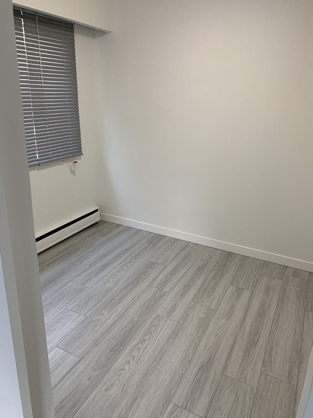 an empty room with wood floors and a window