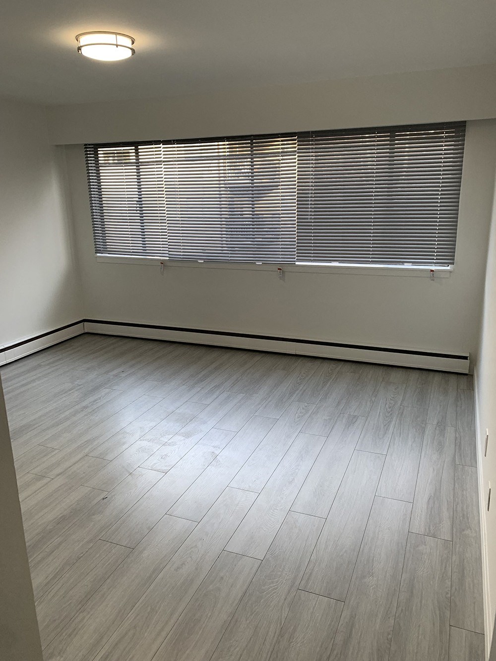 an empty room with wood floors and a window