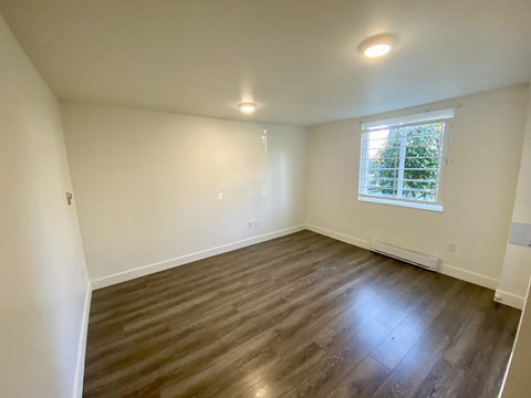 an empty living room with wooden floors and a window