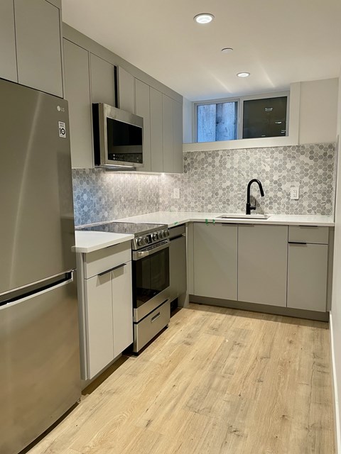 A modern kitchen with a stainless steel refrigerator, microwave, and oven.